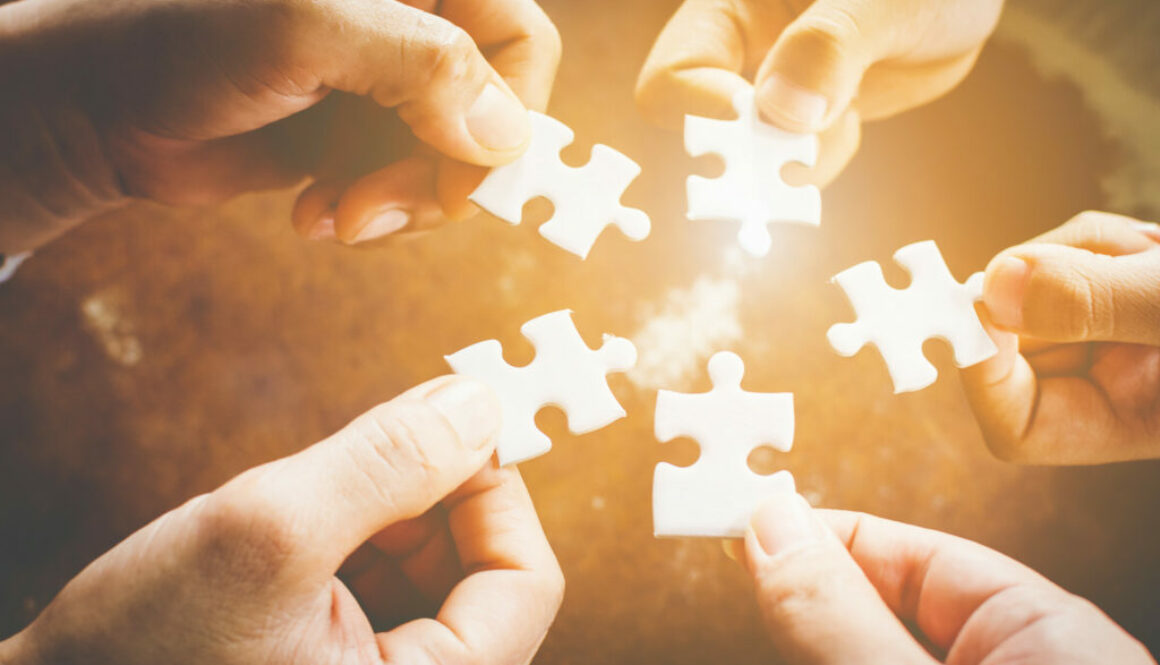 Hand of diverse people connecting jigsaw puzzle. Concept of partnership and teamwork in business